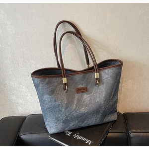Detail of marble pattern tote bag with brown leather handles and golden metal hardware