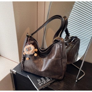 Detail of vintage brown tote bag with suede texture and cute plush lion charm accessory