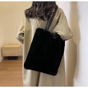 Gros plan du sac fourre-tout en fausse fourrure noire avec de fines bretelles sur un modèle