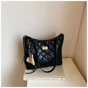 Détail du sac seau noir matelassé avec fermoir doré et pendentif de baseball
