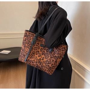 Detailed view of leopard print tote bag with black leather handles and logo plaque