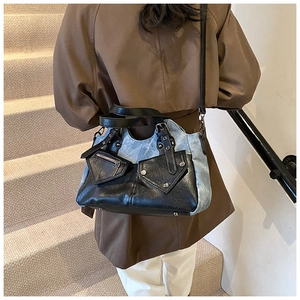 Detail der Tragetasche aus Denim und schwarzem Leder mit metallischen Nietenakzenten