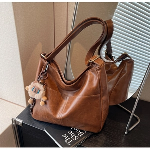 Detail of vintage brown tote bag featuring V-shaped stitching and a cute bear charm
