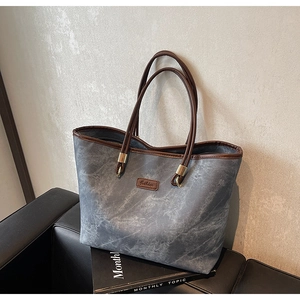 Detail of grey marble texture tote bag with brown leather handles and golden metal buckles