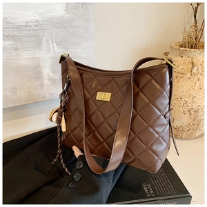 Vue détaillée du sac seau marron foncé matelassé avec fermoir rotatif doré et décor