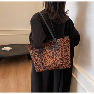 Close-up of leopard print tote bag side view with long leather shoulder strap and logo