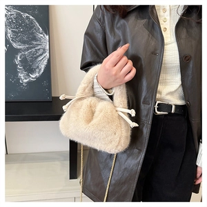 Detailed close-up of light beige plush bucket bag featuring soft faux fur and gold chain strap