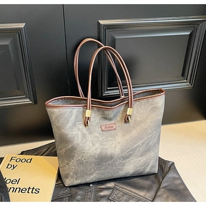 Close-up of vintage grey tote bag with brown leather handles and metallic hardware detail