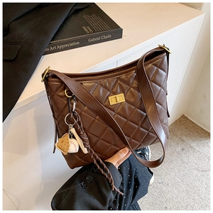 Détail d'un sac seau matelassé marron foncé avec fermoir doré et pendentif baseball