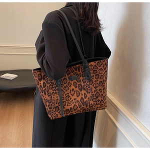 Detailed close-up of leopard print tote bag with black shoulder strap and brand plaque