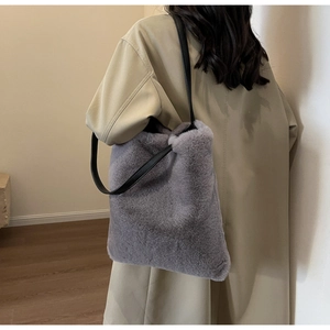 Détail d'un cabas en peluche grise avec anses noires porté sur un trench-coat beige clair