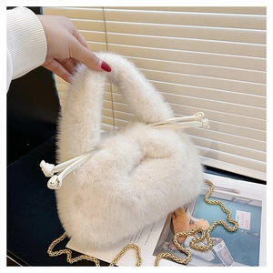 Close-up of white faux fur bucket bag with plush handle and gold metal chain strap detail
