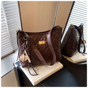 Détail du sac seau matelassé marron foncé avec fermoir doré et breloque sport