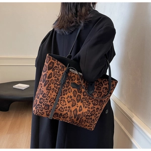 Detail view of large leopard print tote bag with black leather trim and branding