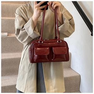 Détail du sac à bandoulière en cuir verni rouge foncé avec deux poches avant sur trench