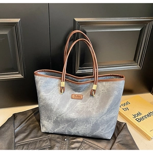 Detail of grey marble texture tote bag with brown leather handles and fashion patch