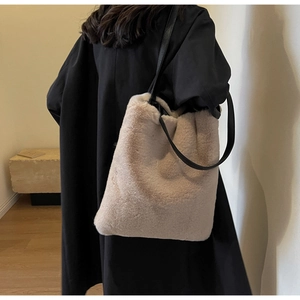 Vue mannequin d'un grand cabas en peluche beige avec des anses en cuir noir sur manteau