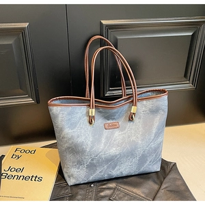 Detail of grey marble texture tote bag with brown leather straps and golden hardware