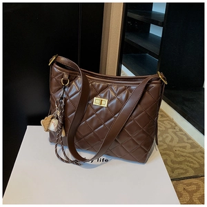 Détail d'un sac seau matelassé marron avec fermoir tournant doré et charme baseball