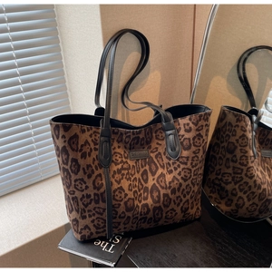 Detail of leopard print tote bag with plush texture and black leather handle straps