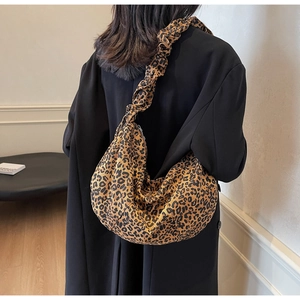 Détail d'un sac hobo à imprimé léopard avec bandoulière froncée sur un manteau noir