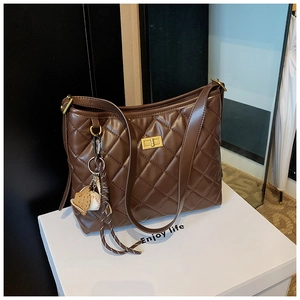 Détail du sac seau marron matelassé avec fermoir doré et pendentif gant de baseball