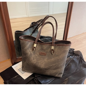 Detail of vintage textured tote bag with Fashion leather label and gold metal hardware