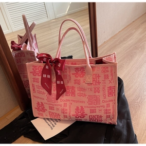 Close-up of pink canvas tote bag with red Double Happiness patterns and silk ribbon bow