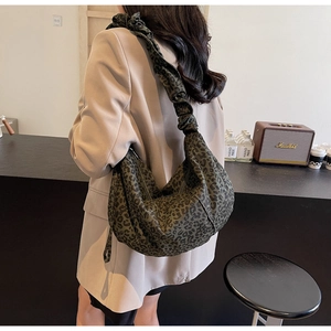 Détail du sac croissant imprimé léopard vert avec bandoulière à volants en toile