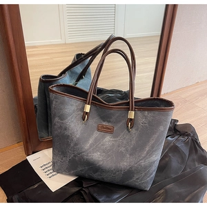 Close-up of marble pattern tote bag with brown leather handles and gold metal accents