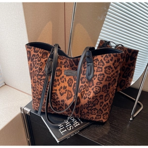 Close-up of leopard print tote bag fabric with leather strap and metal logo tag