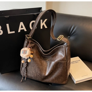 Detail of vintage brown tote bag with adjustable strap and lion plush charm accessory