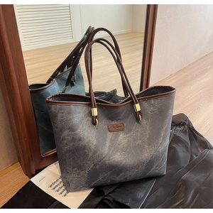 Detailed close-up of a large tote bag featuring gray marble texture and gold hardware