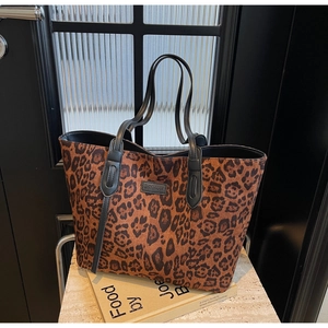 Close-up of leopard print tote bag featuring black handles and leather logo patch