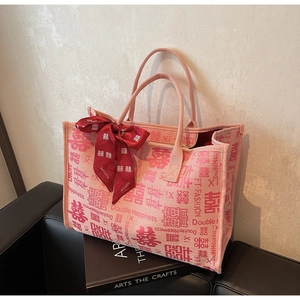 Detail of pink wedding tote bag with double happiness pattern and red silk bow decor