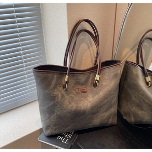 Detail of vintage textured tote bag featuring brown leather handles and marble effect finish