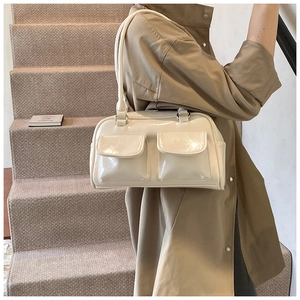 Détail du sac à main en cuir verni crème avec deux poches à rabat et bandoulière ronde