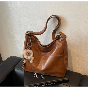 Detail of vintage brown leather tote bag with lion plush charm on a book