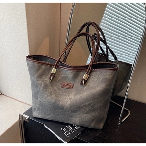 Macro detail of the grey marble texture tote bag with brown leather handles and gold hardware