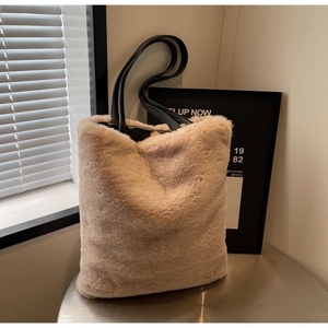 Détail du sac cabas en peluche beige montrant la fourrure synthétique et les anses noires