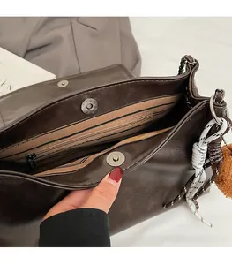 Détail de la boucle magnétique et de la poche zippée intérieure du sac marron foncé