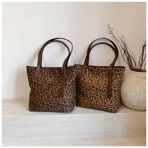 Detail of leopard print tote bags with brown leather straps on stone steps in studio