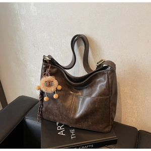 Detail of dark brown vintage PU leather hobo bag with teddy charm and outer pocket