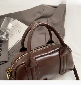 Dettaglio ravvicinato dei manici della borsa marrone scuro con finiture in metallo dorato