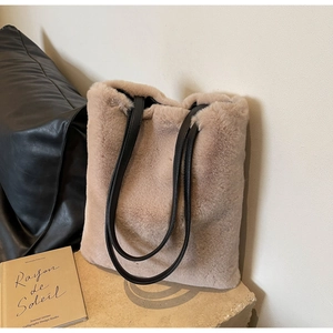 Détail du sac cabas en fausse fourrure pelucheuse avec anses en cuir noir sur socle