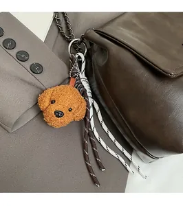 Détail d'un pendentif chien en peluche avec cordons tressés sur sac à main en cuir brun