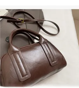 Primo piano di borsa vintage marrone con finiture in ottone su sfondo di tessuto morbido