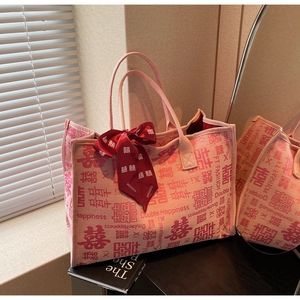 Detail of pink canvas tote bag featuring red Double Happiness prints and ribbon
