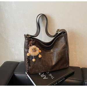 Detail of a vintage dark brown tote bag with a plush lion charm on art books