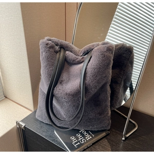 Détail d'un sac cabas en fausse fourrure grise avec anses en cuir noir dans un décor chic